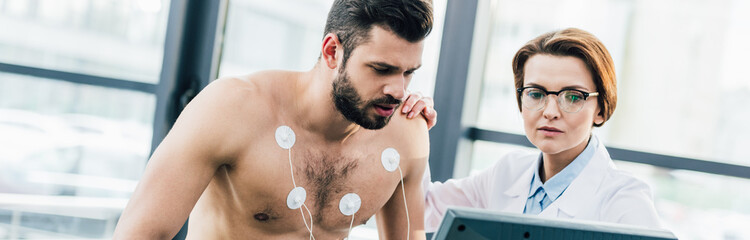 panoramic shot of doctor conducting endurance test near sportsman with electrodes in sports center © LIGHTFIELD STUDIOS