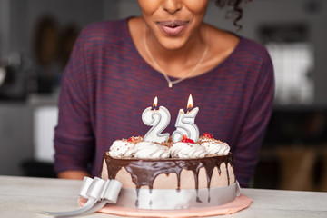African woman blowing birthday candles on cake