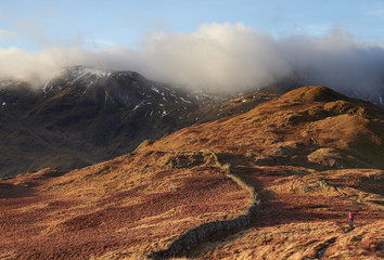 A hiker walking up Hartsop Above How towards Hart Crag and Dove Crag in the Lake District.