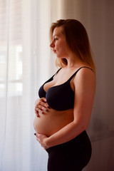 Thoughtful pregnant woman looking out the window