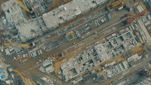 abandoned industrial zone with incomplete buildings and tremendous constructional cranes bird eye view