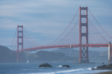 Classic panoramic view of famous Golden Gate Bridge seen from scenic Baker Beach in beautiful golden evening light on sunset with blue sky and clouds in summer, San Francisco, California, USA