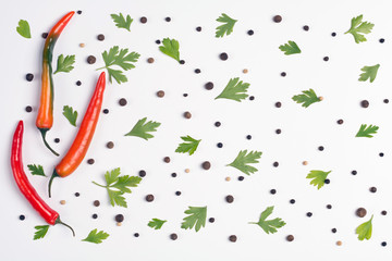 Fototapeta premium Pattern of vegetables. Food background. Composition of chili peppers, parsley and spices on white background. Top view.