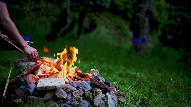 Slow Motion Footatge of a Campfire beeing stoked with a stick in the evening. Shot in 4K