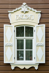 Window with the wooden carved architrave in the old wooden house in the old Russian town.