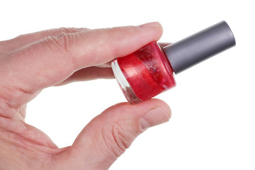 An elderly man holds in his hand a bottle of red nail polish