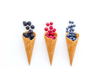 Fresh berries in waffle cones on white background top view
