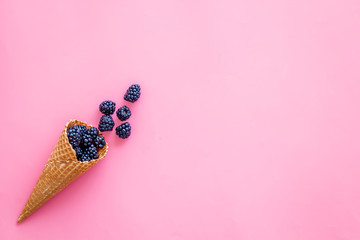 Summer breakfast with fresh berries in waffle cones on pink background top view mockup