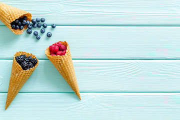 Summer breakfast with fresh berries in waffle cones on mint green wooden background top view mockup