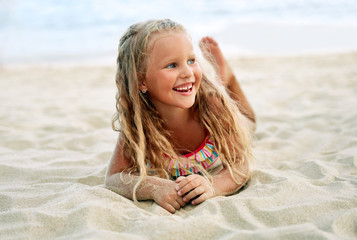 Adorable little blonde girl relax on sandy beach enjoy sea