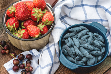 Honeysuckle and strawberry berries in a bowls on garden table.