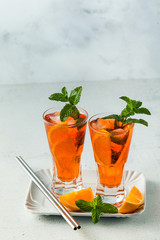 mint summer tea with orange in a tall glass. refreshing soft drink