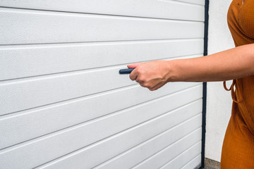  Garage door PVC. Girl or young woman holds remote controller for closing and opening garage door