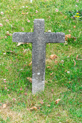 In the green grass stands an old concrete cross