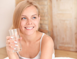 Beautiful smiling young blonde woman waking up and drinking water in the morning.