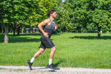 Young handsome man running on gravel road in nature 