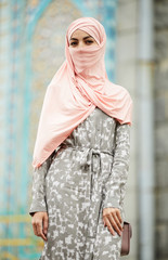 Portrait of beautiful stylish young Muslim woman in pink hijab and summer coat wearing small bag, Islamic fashion concept
