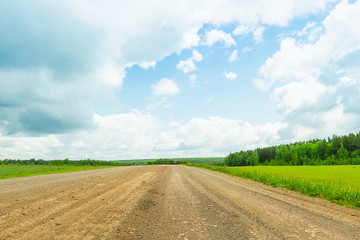 Fototapeta na wymiar Landscape rural road and blue sky. Straight gravel road leading to the horizon.