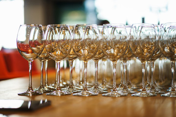 Several rows clear transparent, clean glasses for wine and champagne on counter prepared for drinks.