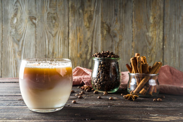 Cold creamy horchata coffee, with coffee beans and spices, wooden background copy space