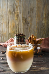 Cold creamy horchata coffee, with coffee beans and spices, wooden background copy space