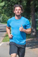 Handsome man running in park with trees in background vertical