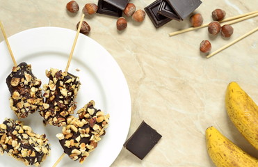 Frozen banana in chocolate and hazelnuts, view from above, copy space