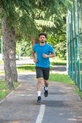 Handsome man running in park with trees in background vertical