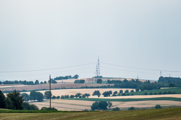 Fototapeta na wymiar Strommasten ziehen sich durchs Feld