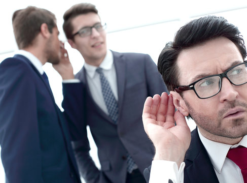 close up.businessman eavesdropping on conversation between colleagues