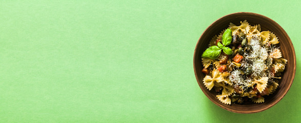 banner of italian pasta butterflies with sicilian vegetable caponata in a clay plate on a green background