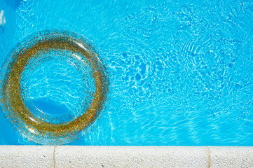 Blue water in the pool and a transparent circle with gold sequins. The atmosphere of rest on the sea, safety on the water.