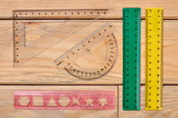 Various plastic rulers on wooden background. Stationery supplies on wooden table.