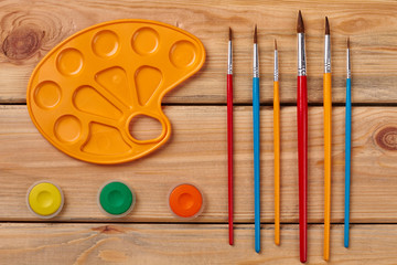 Artist workplace on a wooden background. Watercolor palettes and paint brush. Flat lay composition.