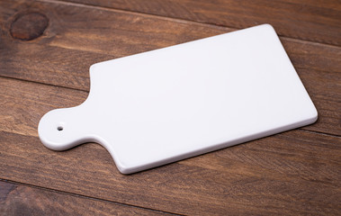 White marble cutting board for the kitchen on brown wooden table.