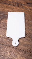 Vertical shoot of white marble cutting board for the kitchen on brown wooden table.