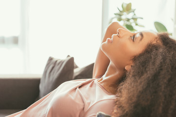 pretty african american woman lying on couch while suffering from summer heat at home