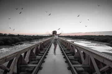 girl jumps on bridge surrounded by birds in the evening