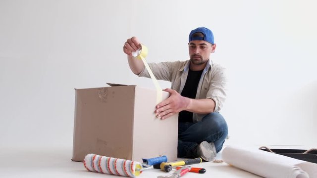 man taping boxes for a move in his empty apartment