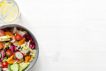 Vegan salad with tomatos, fresh green salad, pepper, cucumber, etc. Top view