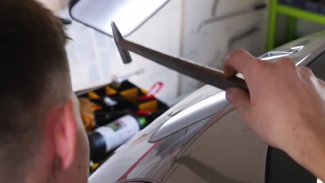 Paintless Dent Repair Removal. Tap Down Tools Dent Rubber Hammer Auto Body. The guy knocks with a hammer on the car to align the dent on technology PDR.