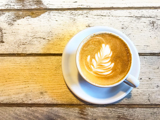 Cup of cappuccino with pattern on old wooden table. 