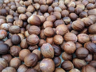 Dark brown nutmeg seeds drying naturally under the sun