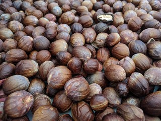 Dark brown nutmeg seeds drying naturally under the sun