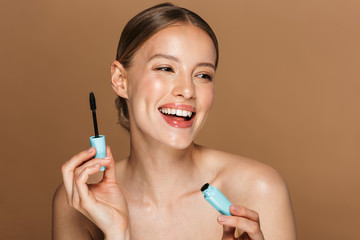 Image of smiling half-naked woman looking aside and holding mascara