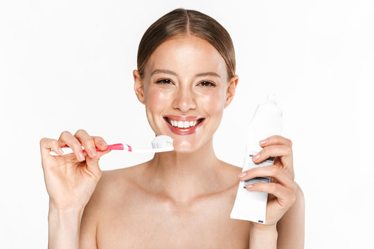 Image of happy half-naked woman cleaning her teeth with toothpaste and toothbrush