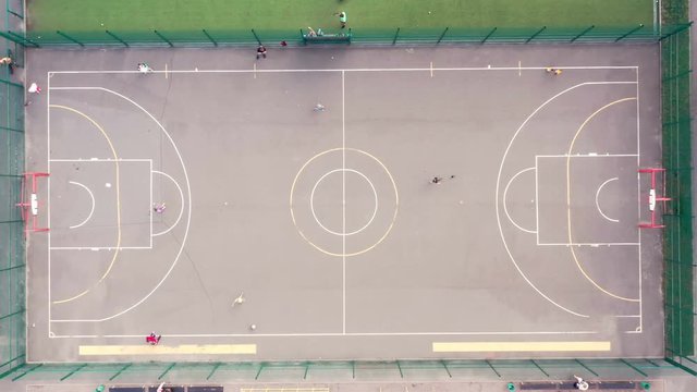 Kids and adults playing at the city playground with football and basketball fields markings. This 3840x2160 (4K) video depicts sport and recreation, happy young new generation. 