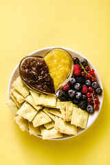 cookies and fresh berries in a plate on a yellow background and marmalade