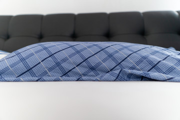 Image of blue pillow in black bed with white blanket