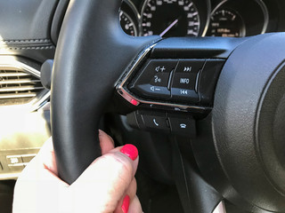 Female hand on the steering wheel inside the car.